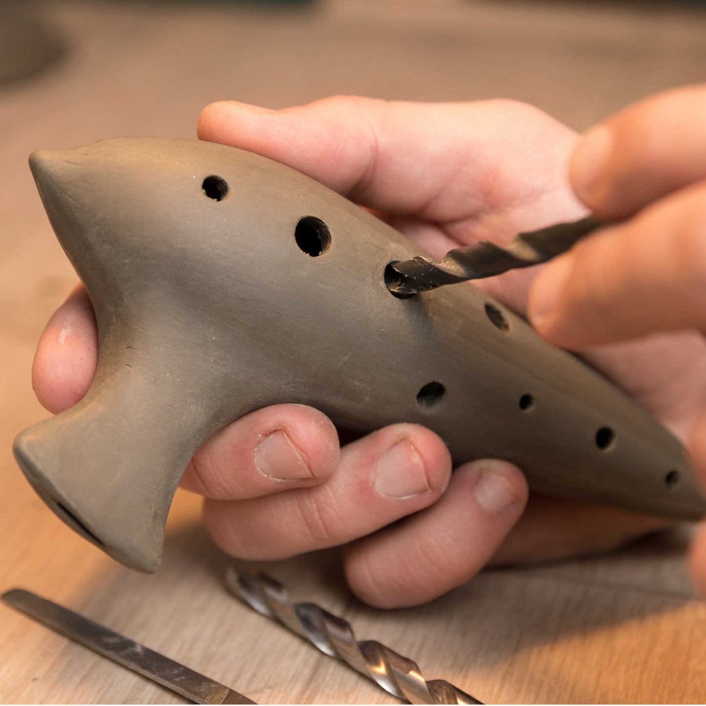 Präzisions-Handarbeit: Manuelles Bohren und Stimmen der Klanglöcher einer Terrakotta-Okarina.