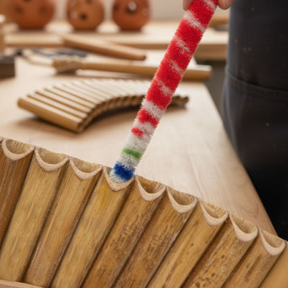 Anwendung des Panflöten-Pflegesets: Ein Reinigungsstab wird sanft in ein Bambusrohr eingeführt zur gründlichen Innenreinigung und Ölung