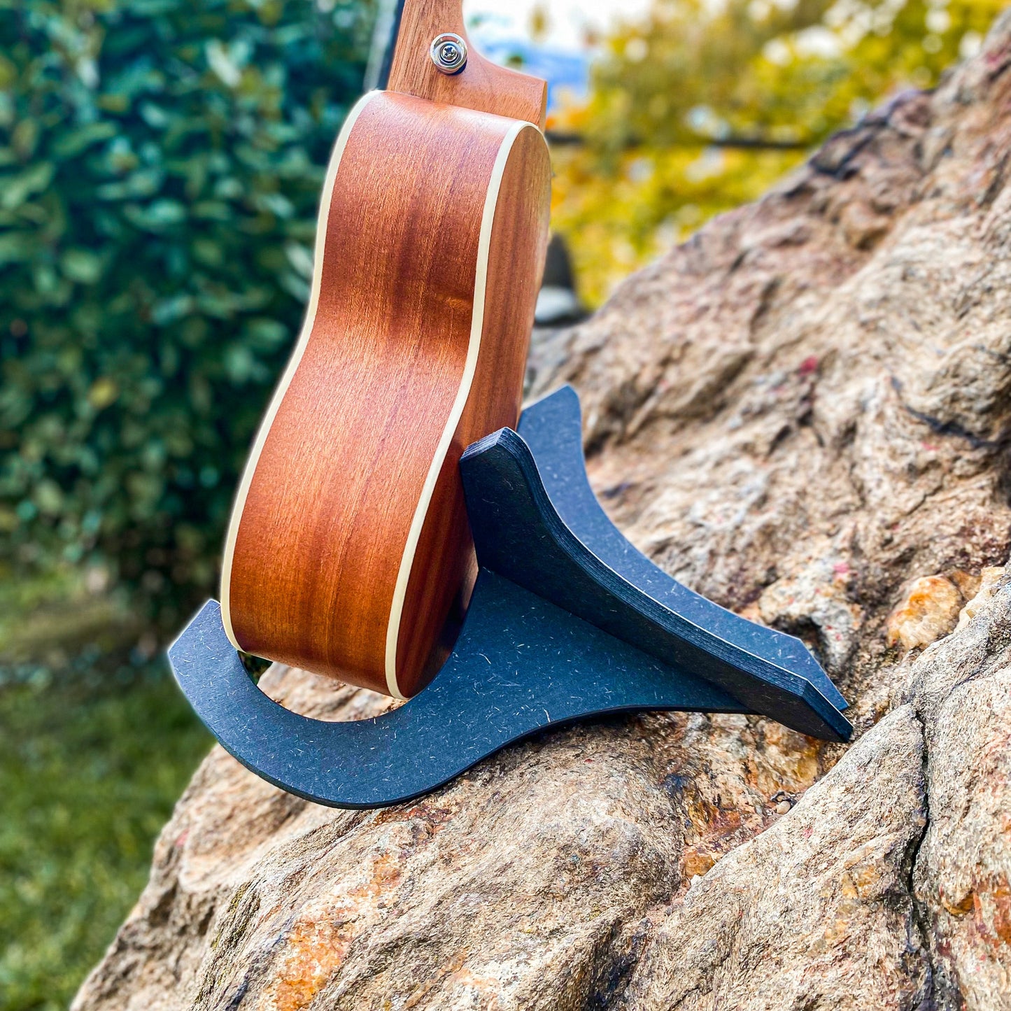 Seitliche Ansicht einer Ukulele sicher platziert im schwarzen Holzständer