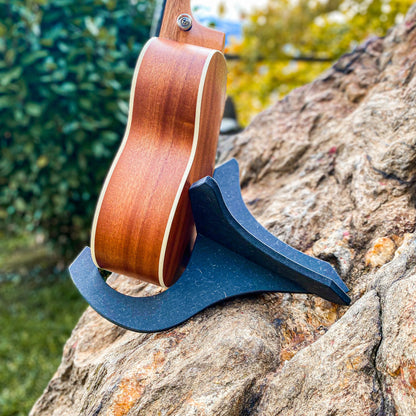 Seitliche Ansicht einer Ukulele sicher platziert im schwarzen Holzständer