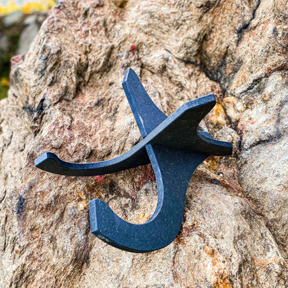 Einsatzbereiter schwarzer Ukulele Ständer aus Holz auf steiniger Fläche